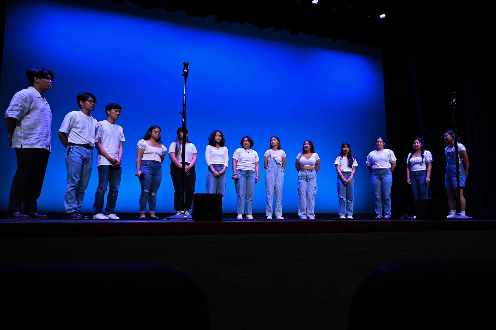 Choir group dressed in white shirts and blue jeans singing.