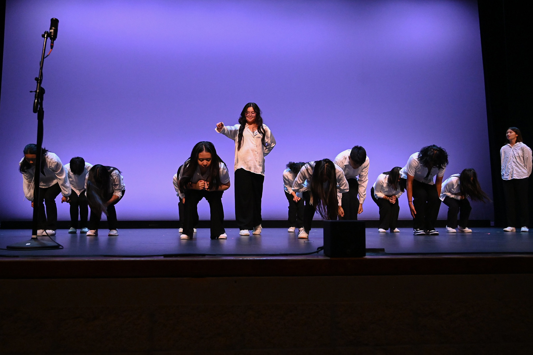 Modern dancers hunched over, 1 dancer standing up.