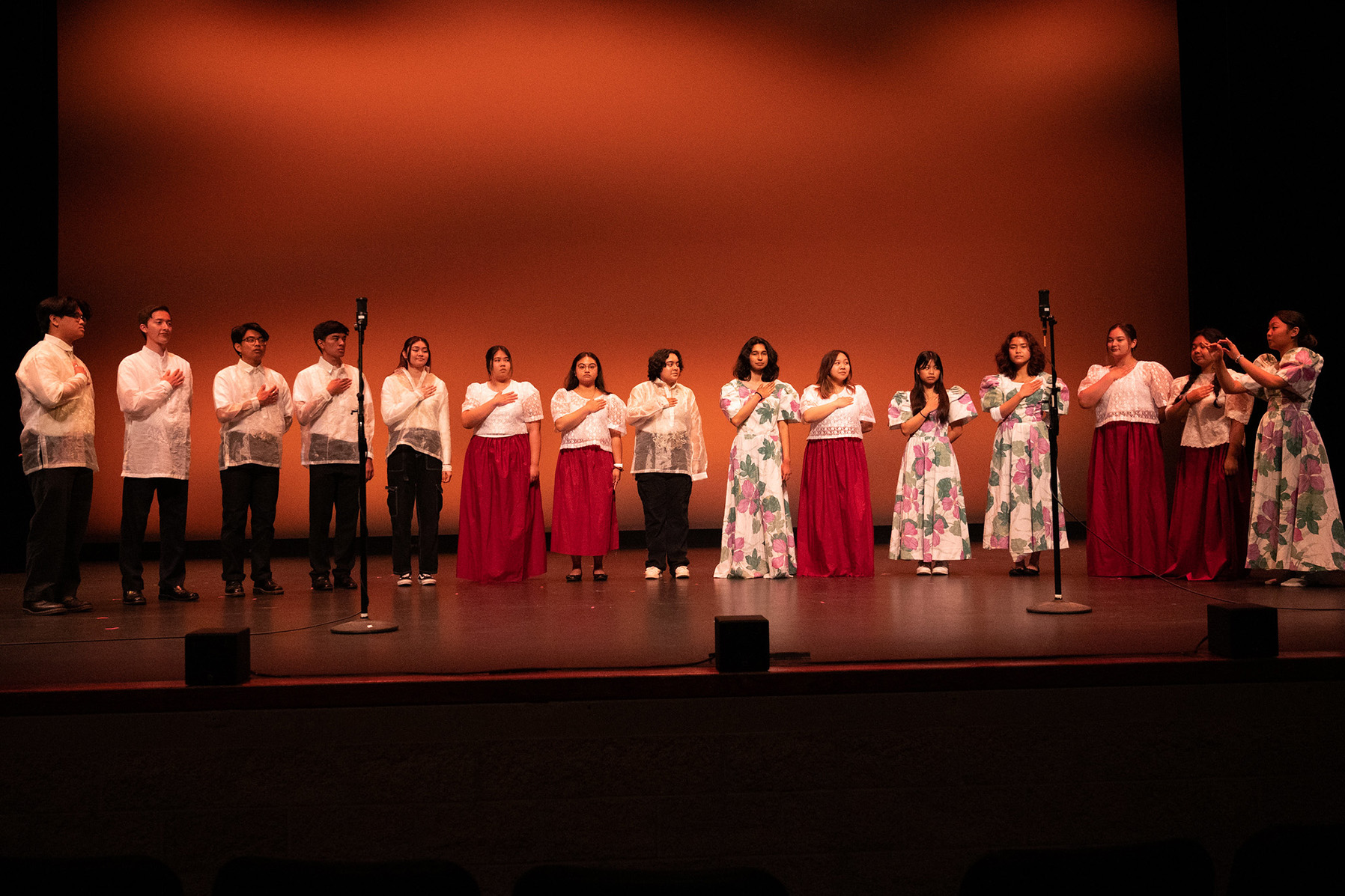 Students in traditional Pilipino clothing singing national anthem.